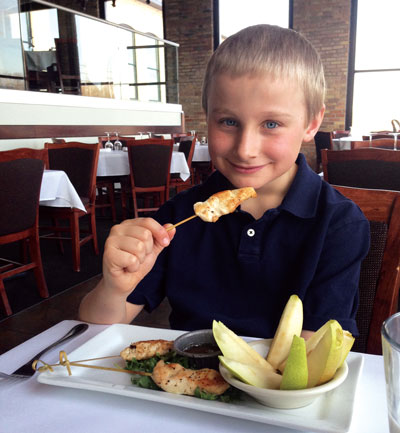 Evan Elrod enjoys a healthy meal of grilled chicken skewers and fresh pears with a honey dipping sauce at Fratellos Waterfront Restaurant in Appleton. Photo by Julia Schnese