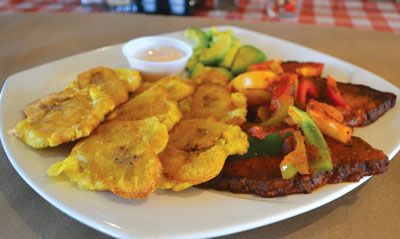 Tostones Tropical — fried green plantain and smoked pork chops with sweet peppers in tropical tomato sauce — at Paninoteca. Photo by Julia Schnese